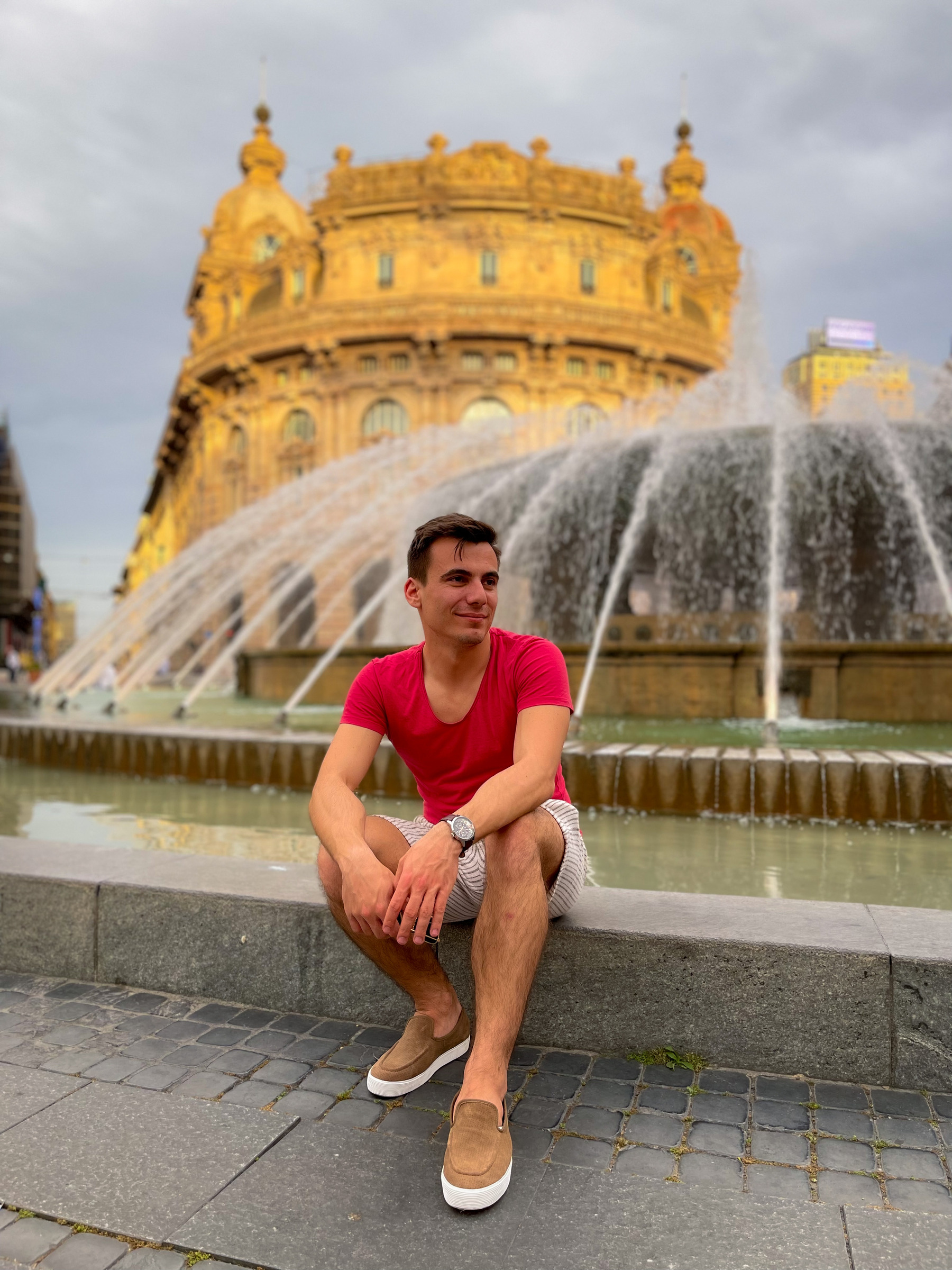 silviu sitting in front of to the fountain in piazza de ferrari in genoa