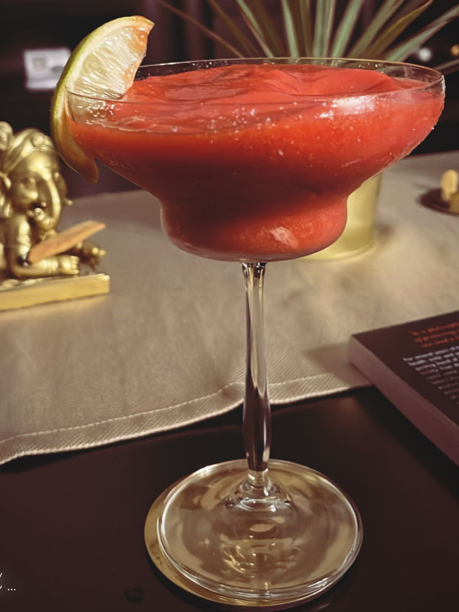 glass of frozen strawberry margarita with a lime wedge garnish